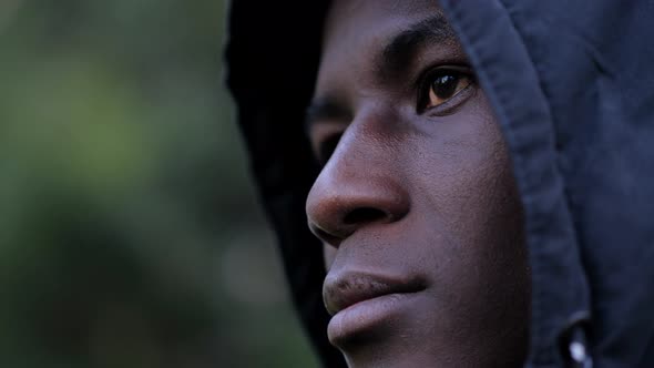 Thoughtful confident hooded young black african migrant-outdoor