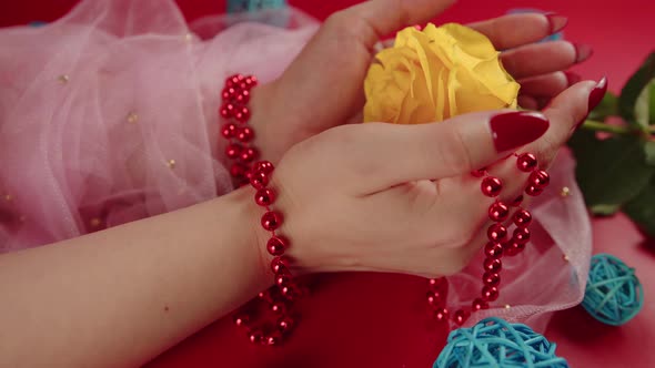 From Above of Crop Anonymous Woman with Red Beads and with Red Manicure Holding a Yellow Rose on Red