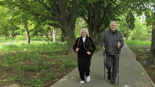 Active Senior Old Couple. Man Training Nordic Walking, Woman Running in Park