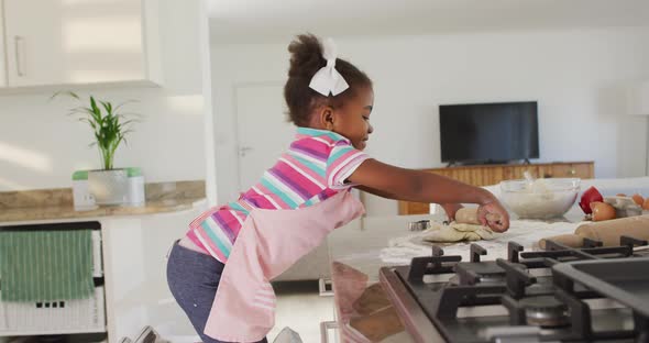 Happy african american girl rolling dough in kitchen