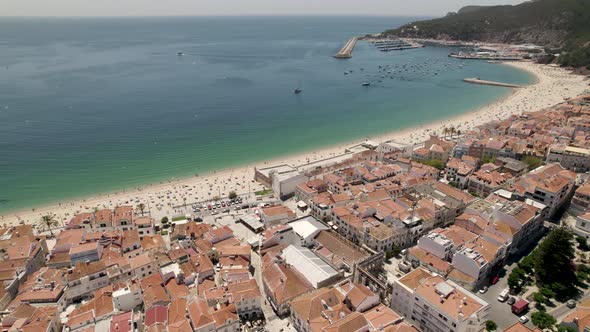 Seascape aerial view of Sesimbra beach full of tourists seen from town, Portugal