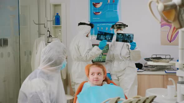 Mother and Daughter with Protective Suit Waiting in Clinic Room for Pediatric Dentist