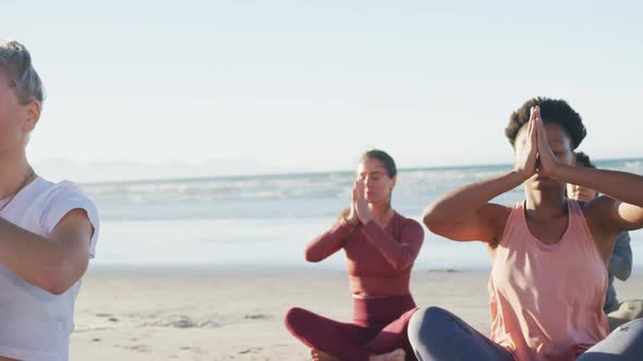 Group of diverse female friends meditating at the beach