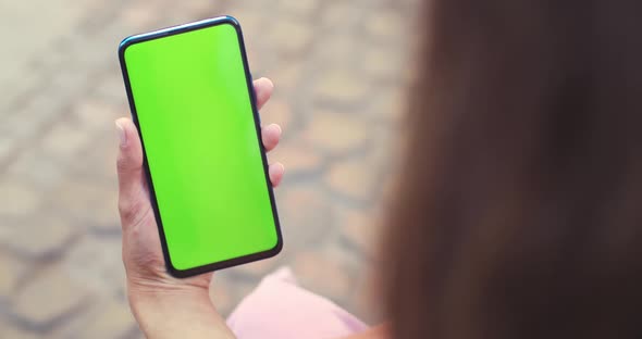 Over Shoulder View of Female Person Holding and Pressing on Smartphone with Mockup Screen While