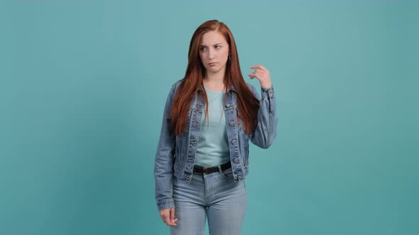 Young Bored Woman Make Blah Blah Gesture with Hand Isolated on Turquoise Background