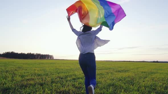 Young Positive Woman Runs Across Field with LGBT Flag Slow Mo