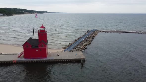 Aerial Around Red Lighthouse on Lake in Michigan with River and Town in Background