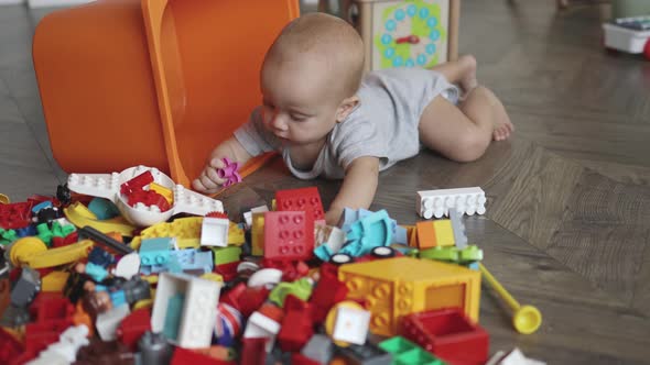 Little Toddler Baby Playing Colorful Bricks and Orange Box on Floor Livingroom