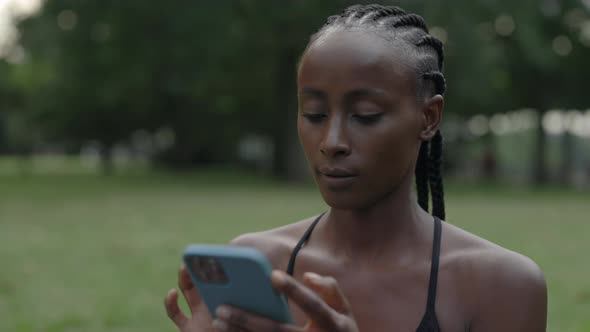 Woman with Braids Using Mobile While Resting During Training