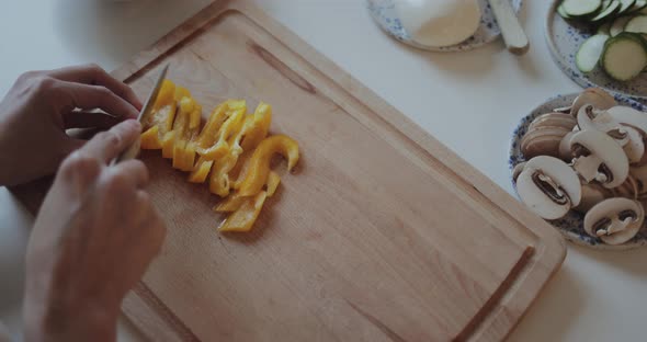 Close-up of woman cutting yellow pepper for homemade pizza