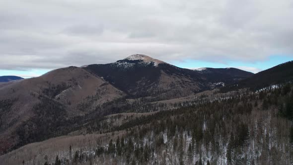 Rising drone shot of a snowy mountain on a moody and cloudy day