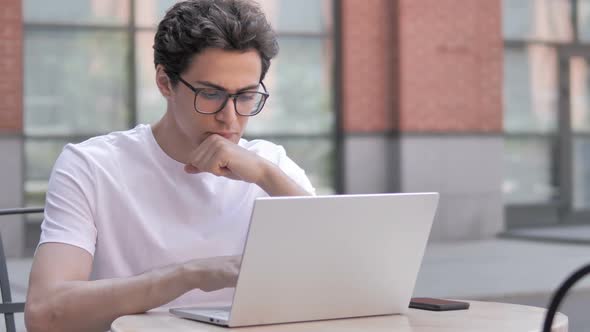 Pensive Young Man Thinking and Working on Laptop Outdoor