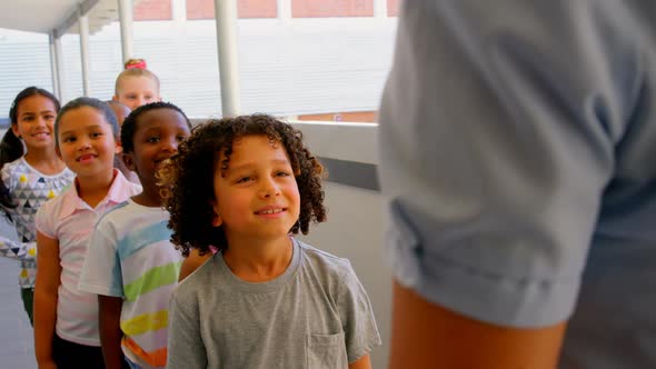 Schoolkids with teacher standing in row in hallway at school 4k