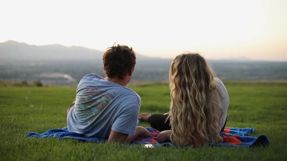 Shot of cute boyfriend and girlfriend laying on a blanket and having a picnic on the grass.