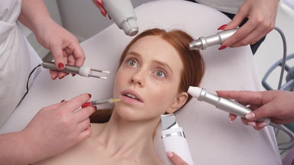 Close-up of a Young Woman's Face with a Scared Expression. Many Hands Hold Cosmetic Tools Close To a