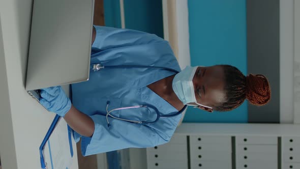 Vertical Video Portrait of Woman Nurse Sitting at Desk and Using Laptop