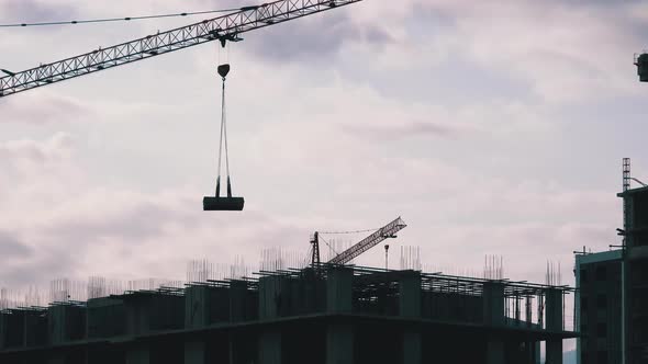 Tower Crane on a Construction Site Lifts a Load at High-rise Building