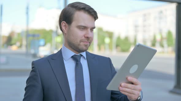 Businessman Celebrating Online Win on Tablet Outdoor