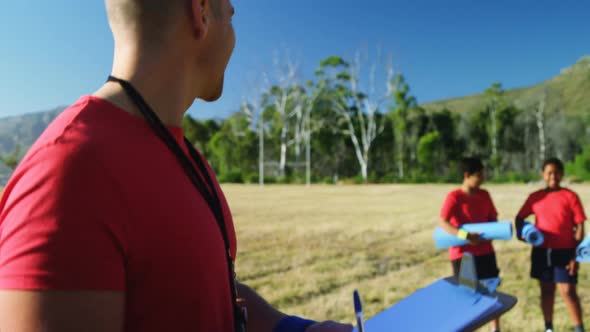 Male trainer writing on a clipboard in the boot camp 4k