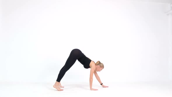 A woman doing yoga exercises on a white background at home.