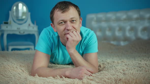 Smiling Young Man Lying on Bed and Looking at Camera