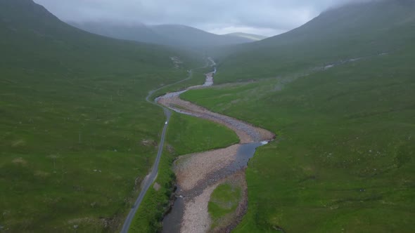 Pan up shot reveals car passing down winding road