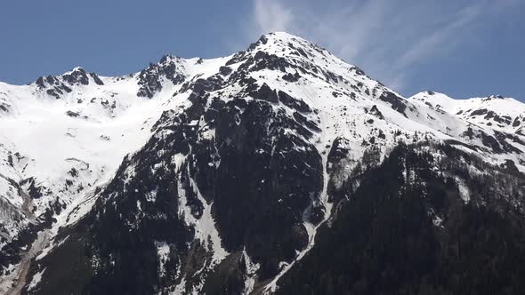 Treeless and Snowy Hill at Top of The Forested Mountain in Sunny Spring Day