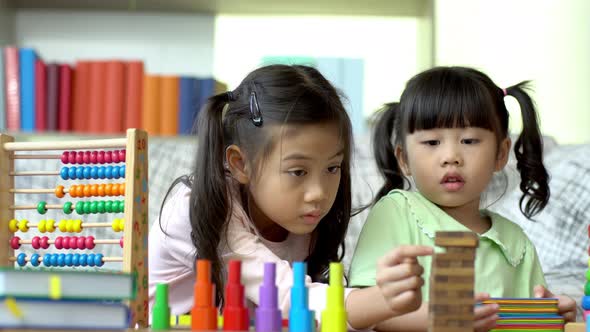 A Beautiful Asian mother busy working at home while looking after and teaching her children on a lap