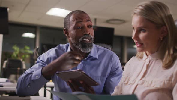 Professional businessman and businesswoman discussing over a digital tablet in modern office in slow