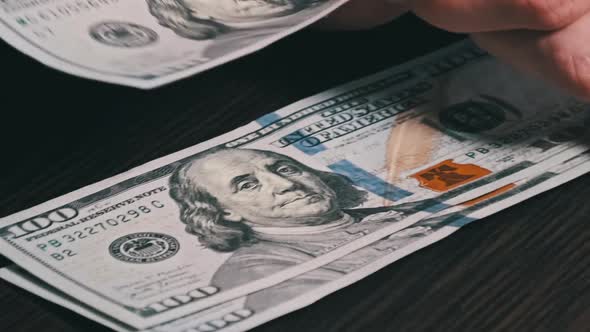 Counting New Hundred Dollar Banknotes on a Black Wooden Table