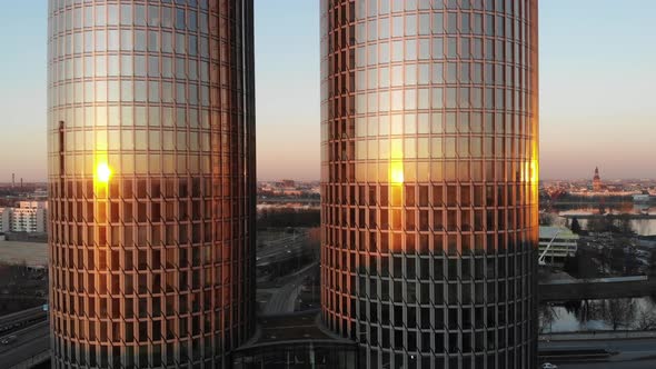 Revealing aerial shot of two glass high rise office and apartment buildings with sunset reflecting i