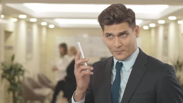 Annoyed Businessman Listening To Yelling in Smartphone. Portrait of Irritated Young Caucasian Man