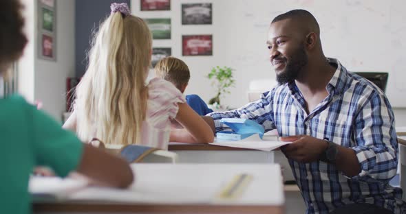 Video of happy african american male teacher clapping hands with caucasian girl