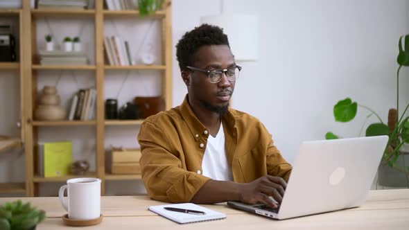 African Man in Glasses Works at Home Background of White Interior Spbas