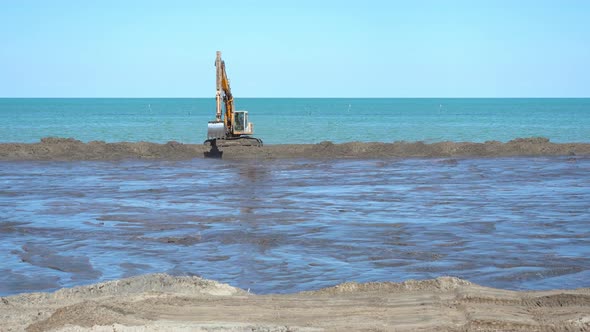 Excavator Quickly Moves to the Sides to the Construction Site on the Beach
