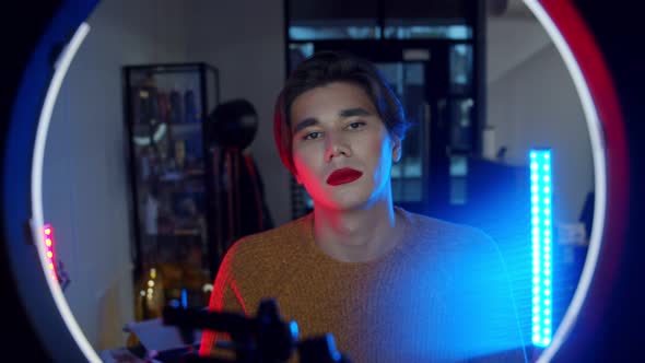 Makeup Studio - Young Handsome Man with Bold Red Lipstick Sitting in Neon Lighting