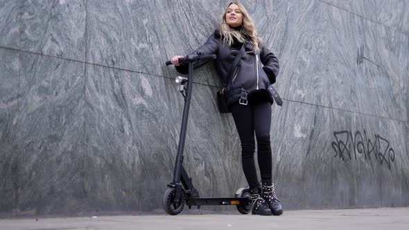 Beautiful Blond Woman Posing with Her Electric Scooter