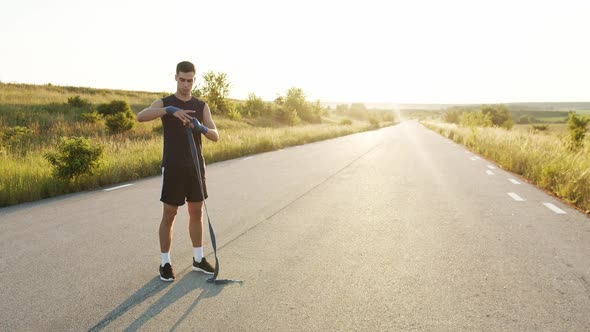 Young Athlete Wrapping Hand Into Tape Before Workout on Road Out of City