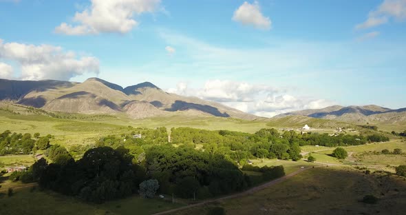 Verdant Trees And Majestic Mountain Scenery In A Rural Village. wide aerial