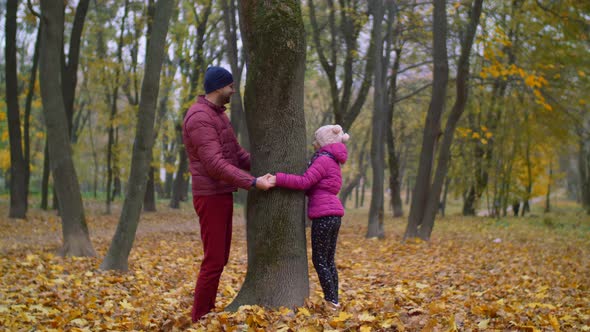 Joyful Father and Kid Playing Hide and Seek in Autumn