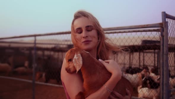 A girl holding a baby goat during sunset Epic shot, Goats farm