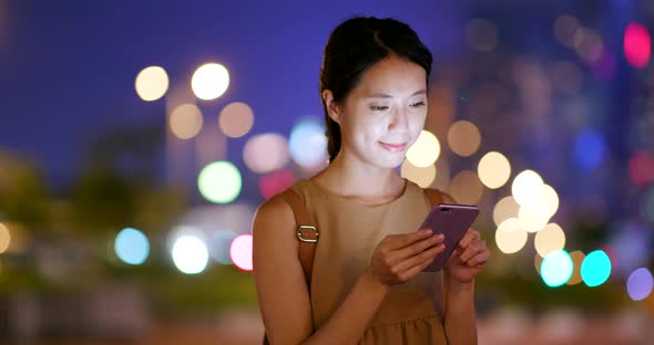 Woman use of mobile phone in city at night