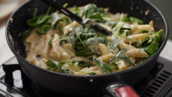 Crop person preparing pasta in frying pan