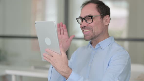 Portrait of Video Call on Tablet By Middle Aged Man in Office