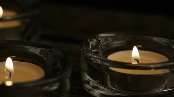 Tea candles with flaming wicks on a wooden background - CANDLES 011