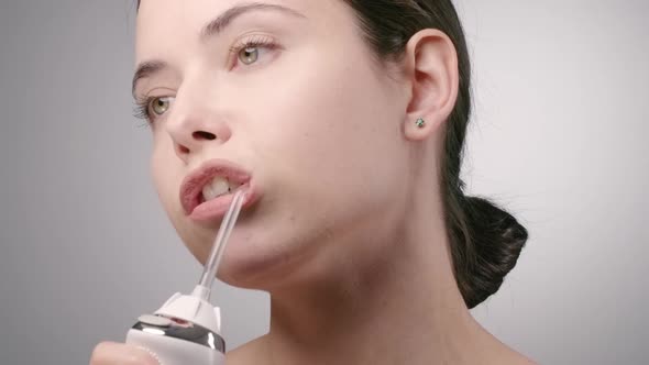 Young Brunette Cleaning Teeth with Water Flosser 
