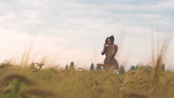 Beautiful Young Woman Walks in a Wheat Field