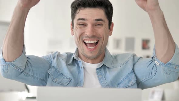 Casual Young Man Celebrating Success at Work