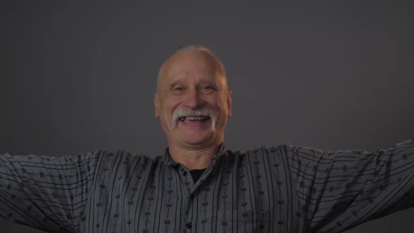 Old Man with Mustache Looks Straight Spreads Arms and Smiles