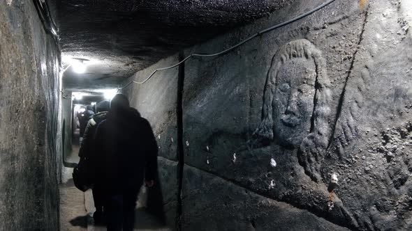 Tourists on the tour in a salt mine in Romania. Narrow pathway, stone walls